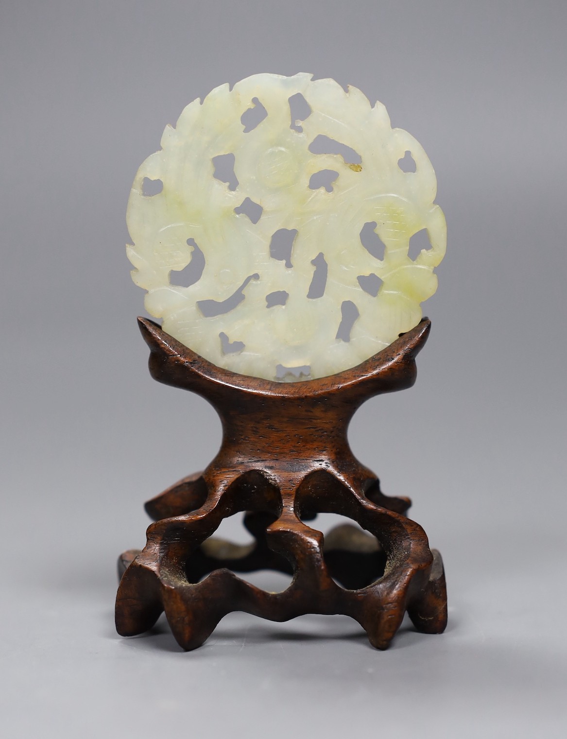 A Chinese jade disc and wood stand, 9cms high